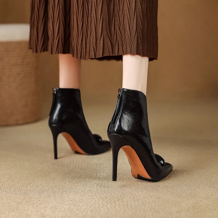 Back view of model wearing black ankle boots with zip closure