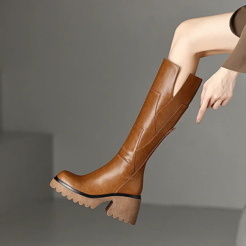 Bottes hautes noires pour femme, design chunky, zip sur le côté, talon carré et tige robuste.