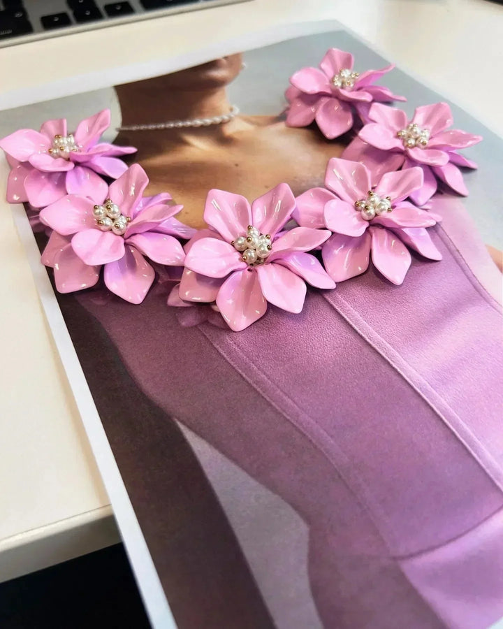 Robe courte rose sans manches avec détails floraux et encolure ajustée, parfaite pour les fêtes d'été.
