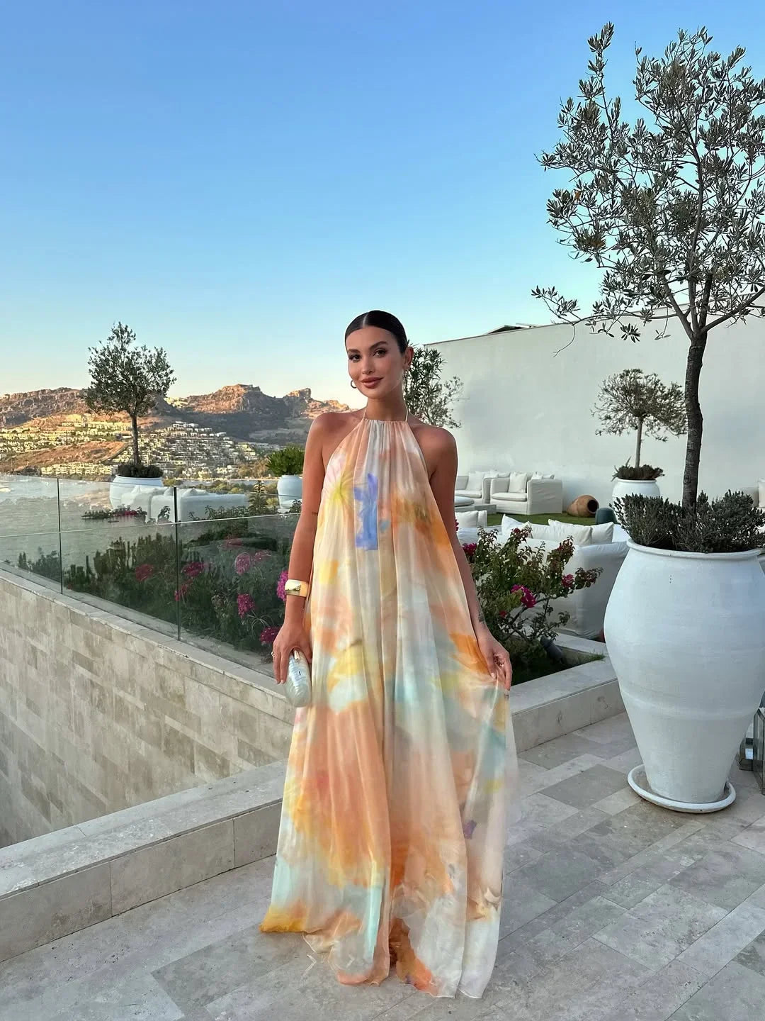 Robe longue femme orange, imprimée, dos nu, en coton léger, avec des bretelles fines et un motif floral vibrant.