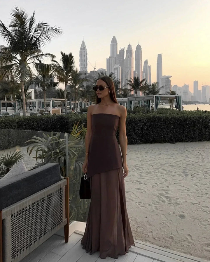 Robe longue asymétrique sans manches en tissu fluide, col bustier, détail à étage pour un look élégant en soirée.